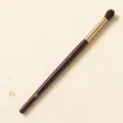 A soft, fluffy, tapered eye blending brush on a slim handle.