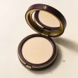 An open round compact of pressed pale powder.