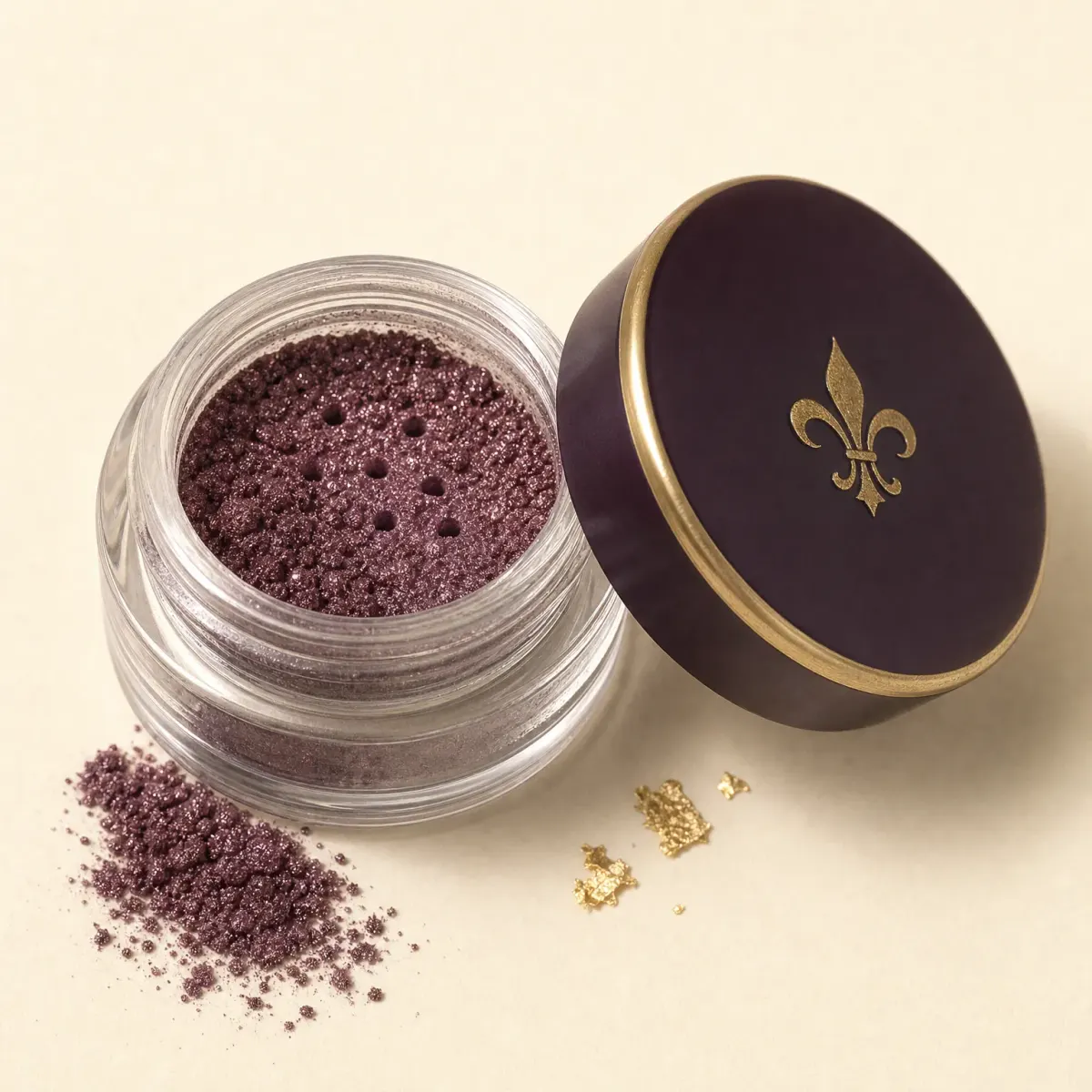 A tiny open jar of violet-bronze loose pigment with a pinch spilled.