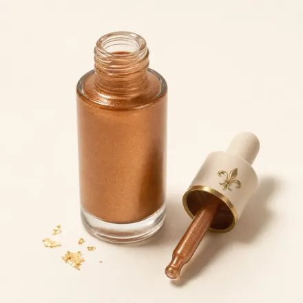 A dropper bottle of shimmering golden-bronze bronzing drops.