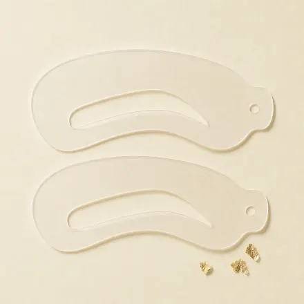 A pair of translucent brow stencils.