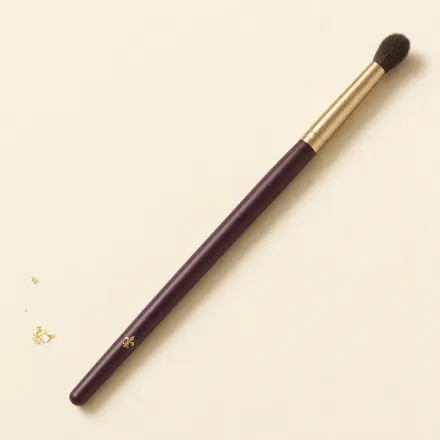 A soft, fluffy, tapered eye blending brush on a slim handle.