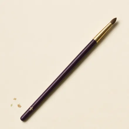 A small, pointed crease brush on a slim handle.