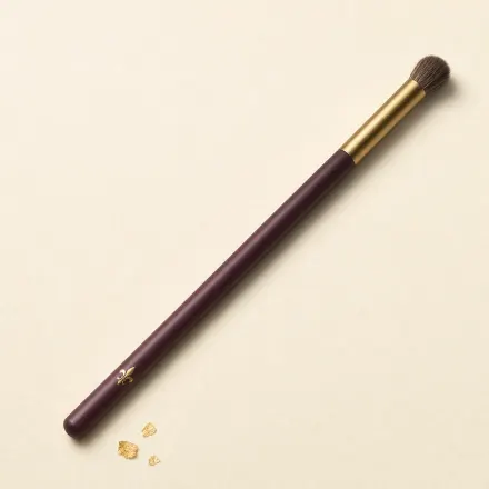 A small, rounded eye blending brush on a slim handle.