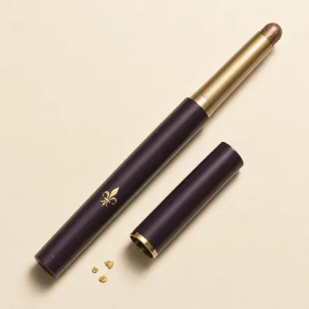 An uncapped slim eyeshadow stick with a shimmering bronze tip.