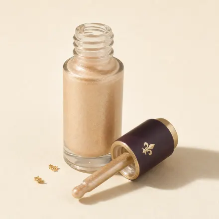 A dropper bottle of pearlescent champagne liquid highlighter.