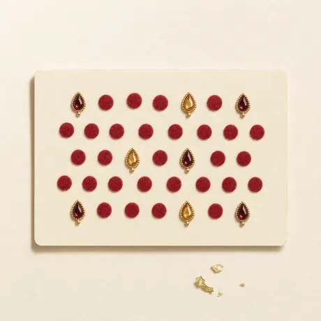 A card of stick-on bindis: red dots and jewelled teardrops.