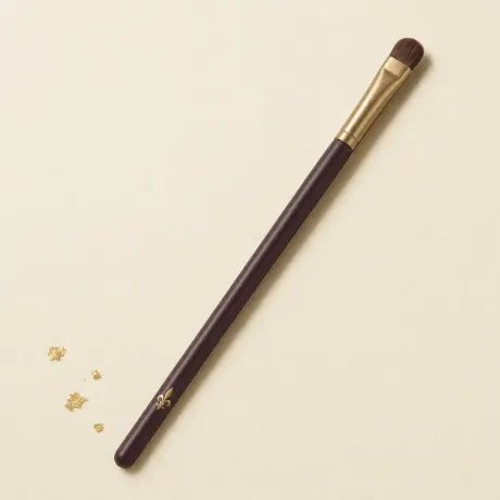 Illustration: A small, flat eyeshadow shader brush on a slim handle.