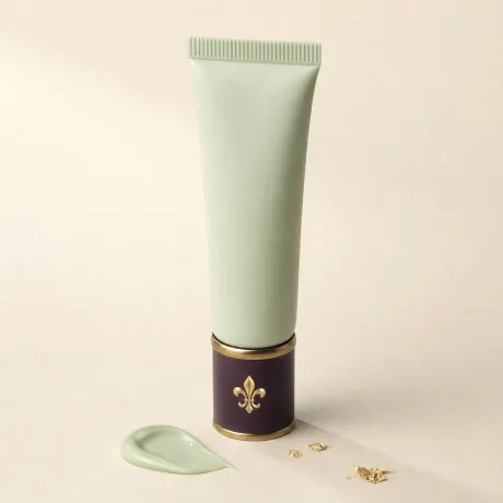 A squeeze tube of mint-green primer beside a dab of green cream.