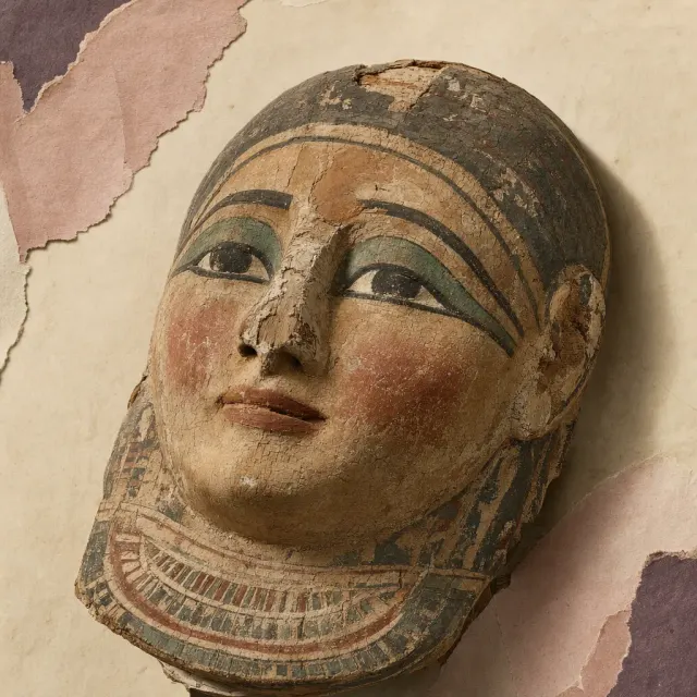 The painted face of an Egyptian coffin lid, carved wood under a finely cracked white ground: long black lines drawn round the eyes, green on the lids and red on the mouth, the paint rubbed to bare wood along the nose.